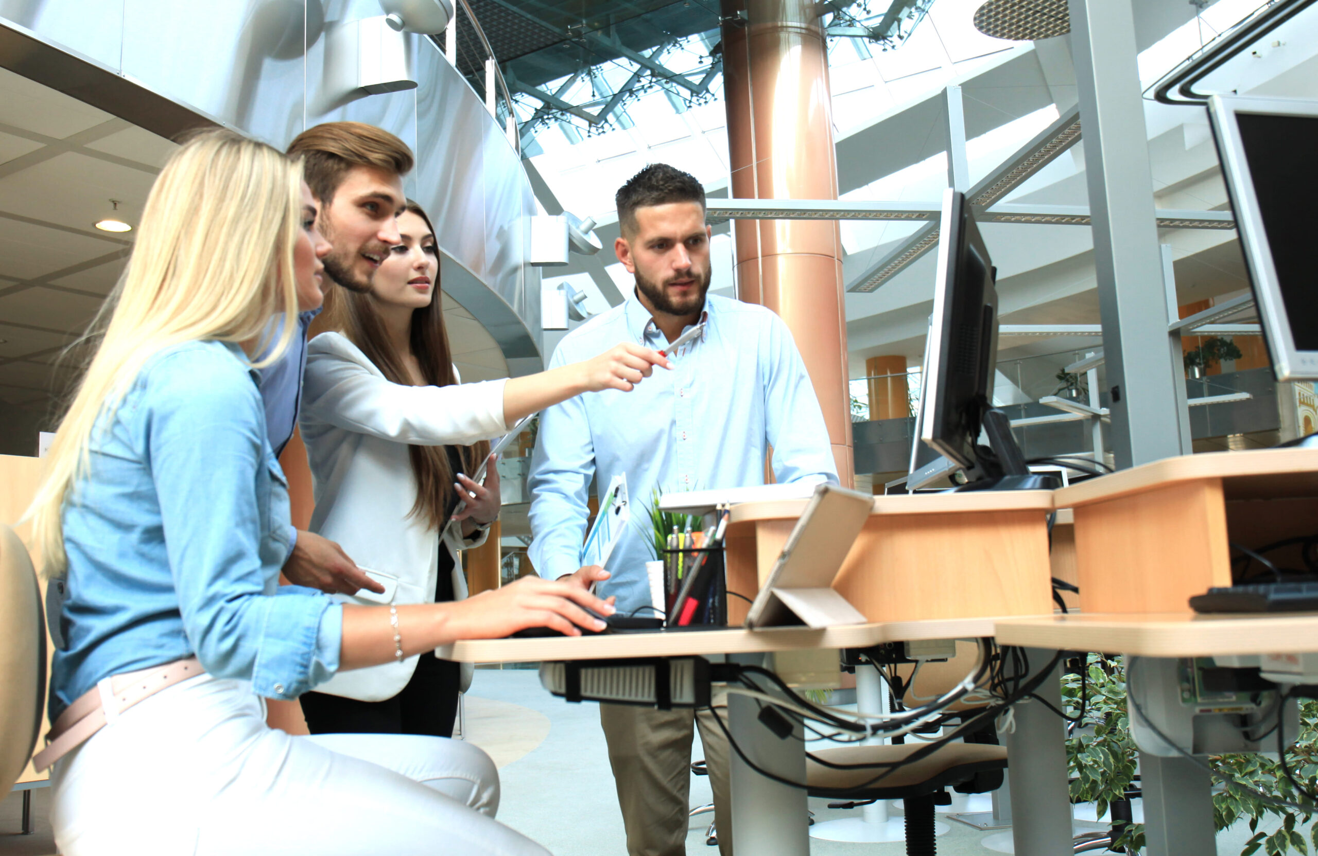 group-young-people-casual-wear-sitting-office-desk-discussing-something-while-looking-pc-together