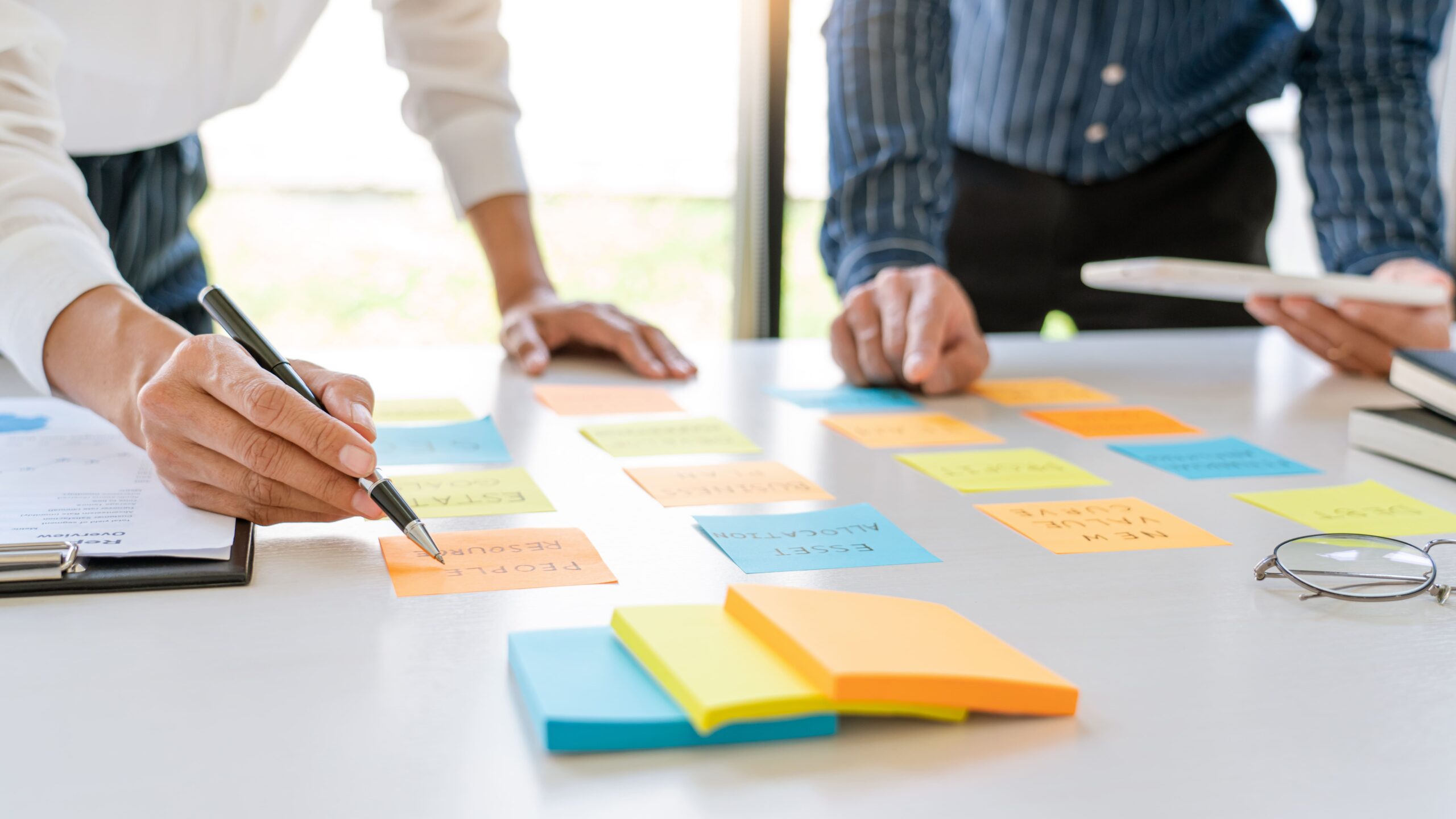 young-business-workers-posting-with-sticky-notes-stickers-reminders-creative-brainstorming-board-colleague-modern-co-working-space