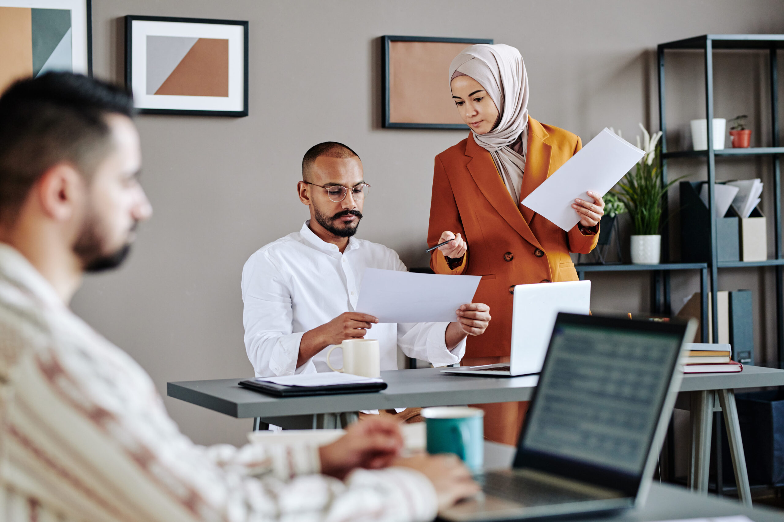 young-muslim-female-male-economists-discussing-financial-papers